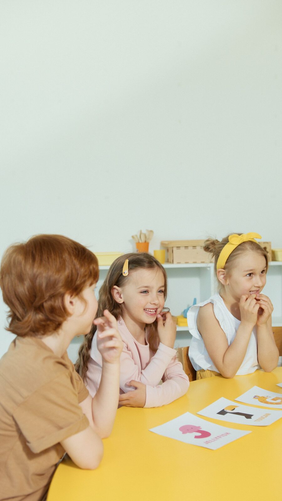 Children laughing together around a bright classroom table during a group session