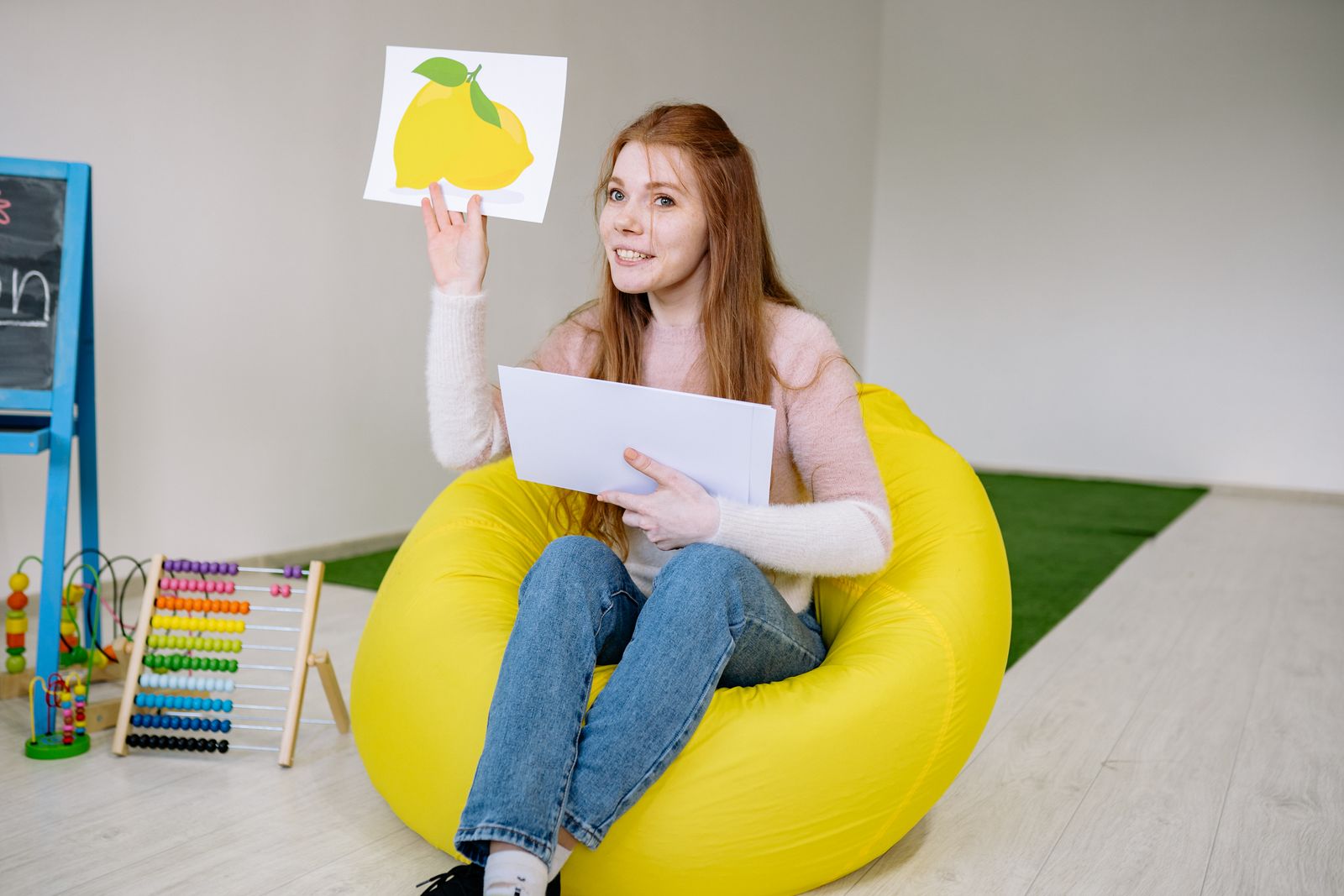 A therapist sitting on a bean bag holding a picture card during a relaxed session