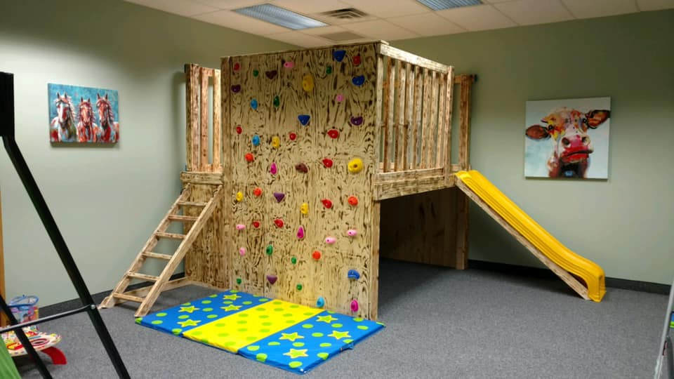 Treatment room with a wooden climbing structure, slide and climbing wall