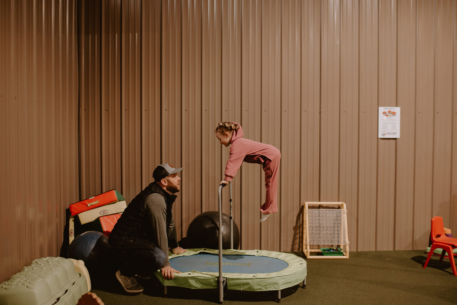A therapist and child at a mini-trampoline on green turf