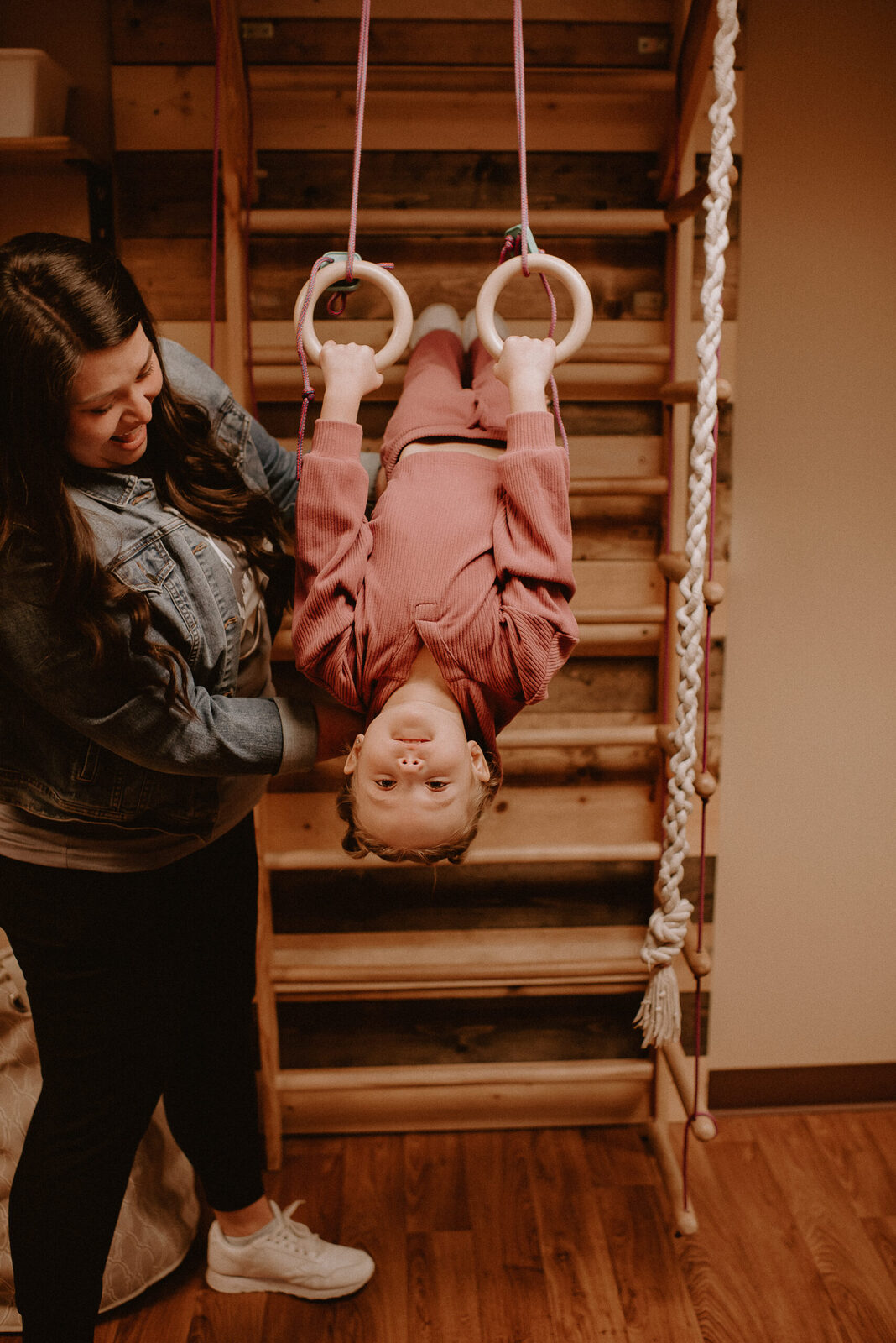 A Game Changer therapist spotting a child on the gymnastic rings in the clinic play gym