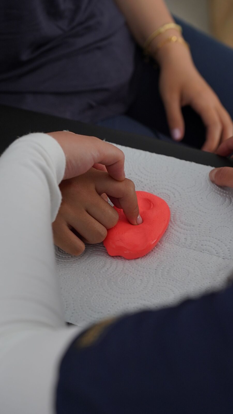 Close-up of therapy putty stretched between two hands during a fine-motor exercise