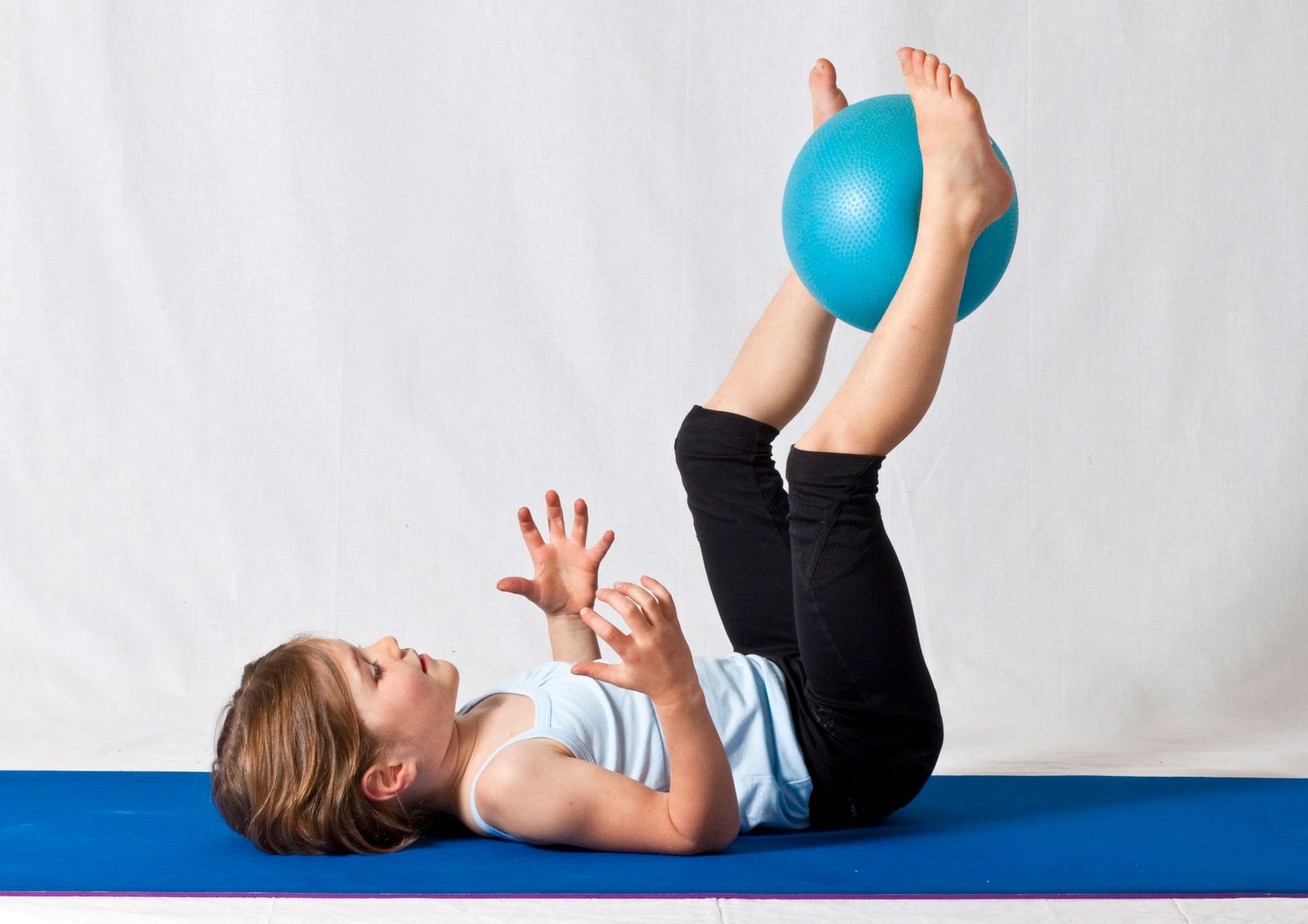 A child doing balance work on a blue therapy ball during physical therapy