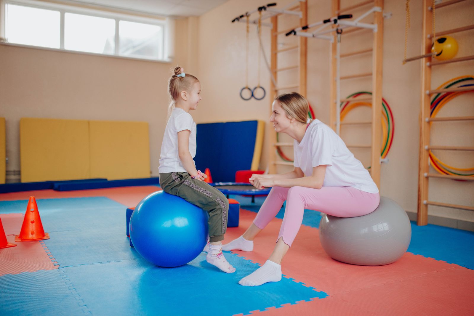 A parent and child working together on exercise balls during a session