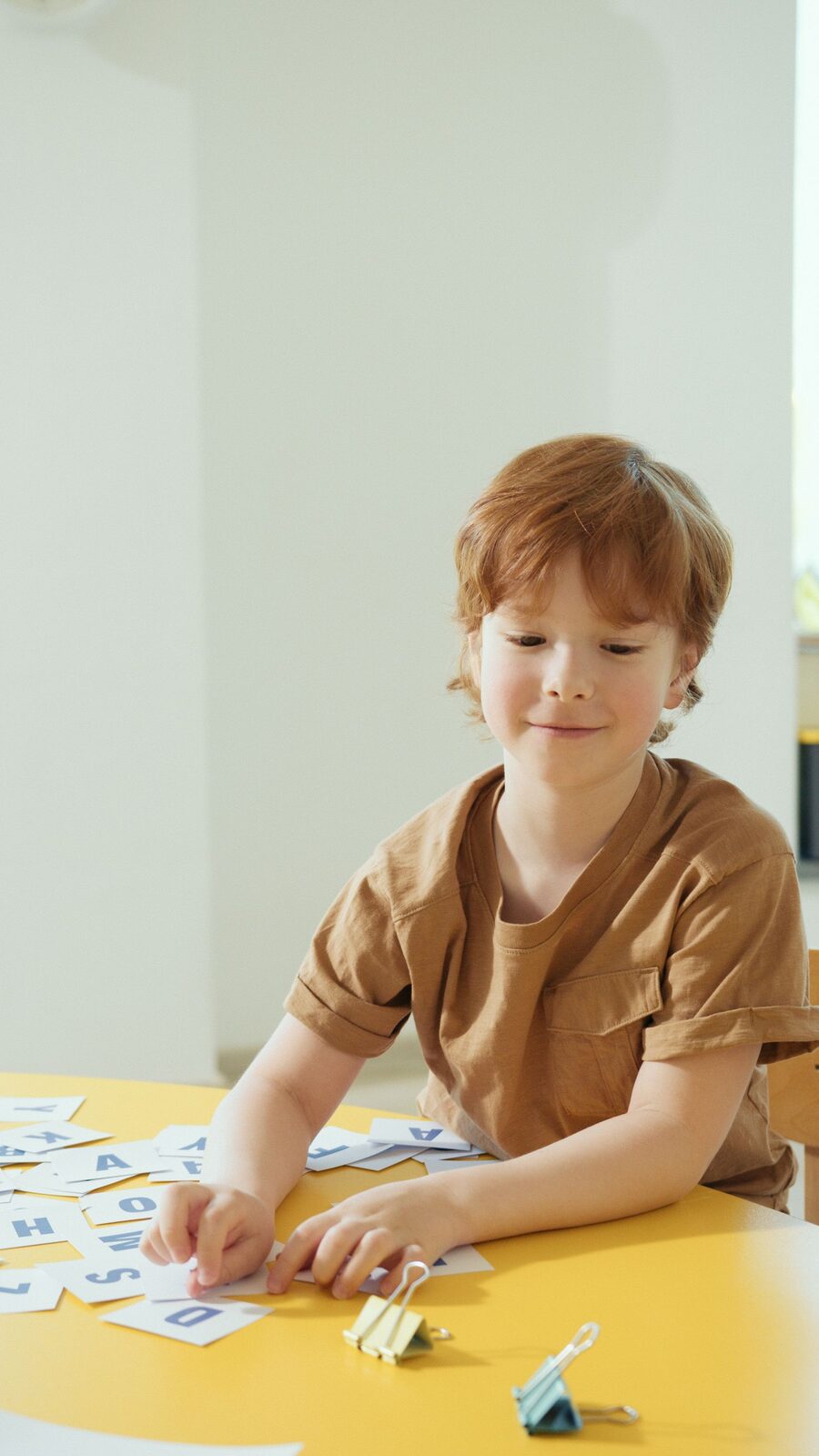 A child arranging letter cards in a bright therapy room during speech work